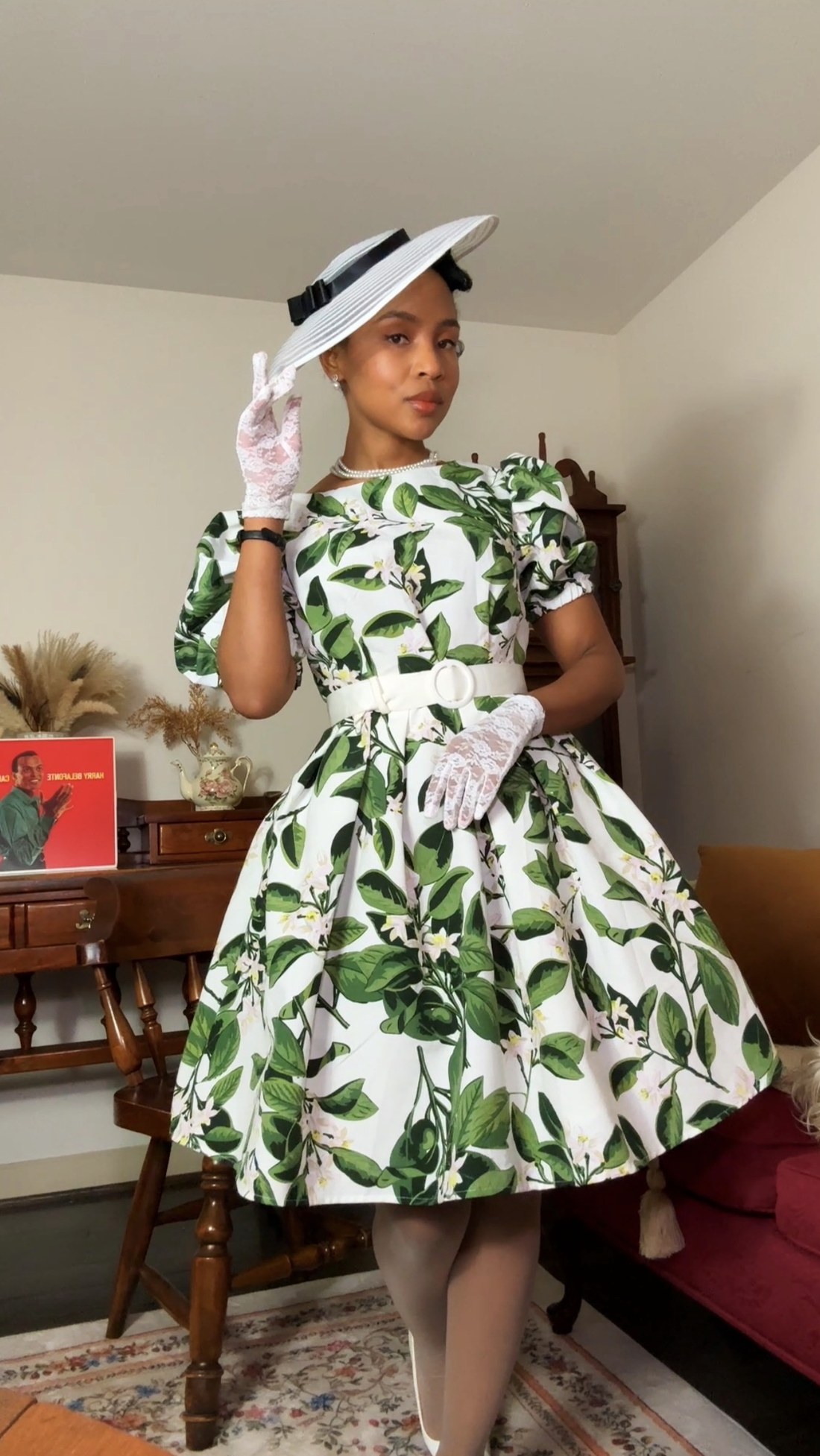 Cazlinn Carstens in a green leaf-print dress and wide-brim hat in her vintage-styled studio